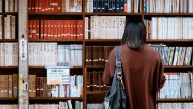 Людина читає книги в бібліотеці на полицях.