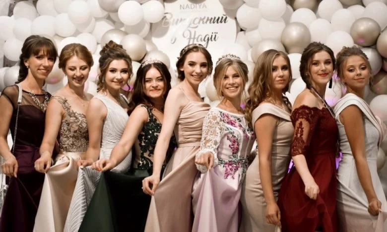Дівчата в сукнях на фоні куль з привітанням