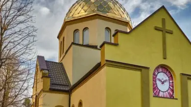 Жовта церква з золотим куполом та хрестом на фоні неба