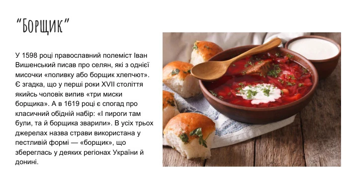 Миска борщу з хлібом та сметаною на дерев'яному столі.